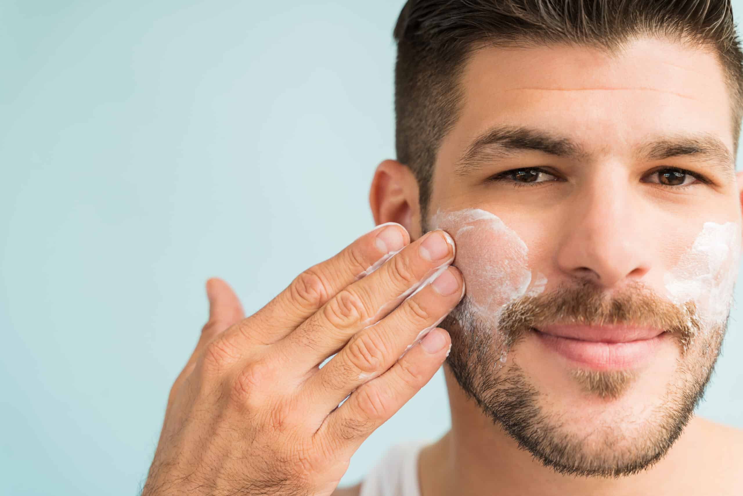 Handsome Latin Man Applying Moisturizer On Face mens skincare