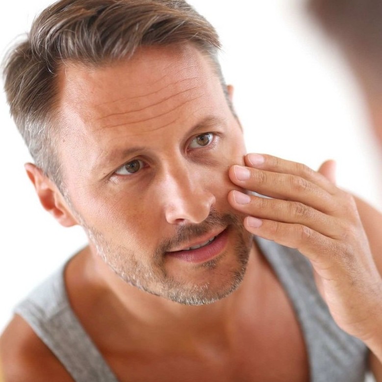 A man with healthy skin applies Scenturie's Natural Enhancing Facial Moisturiser to his face.
