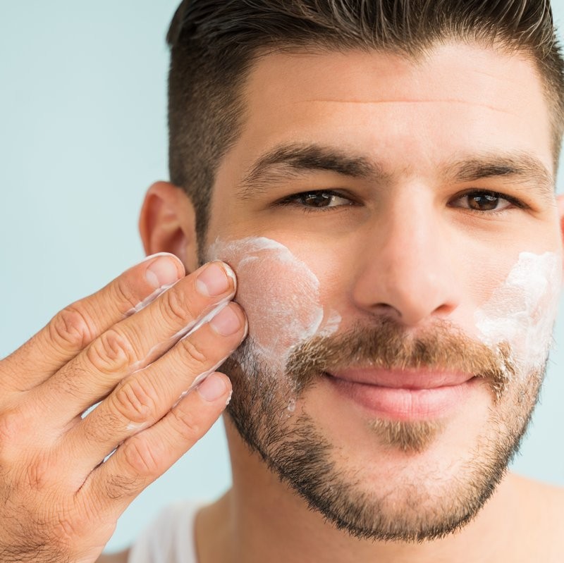 A man with healthy skin applying Scenturie's Natural Hydrating Face Cleanser in a bathroom.