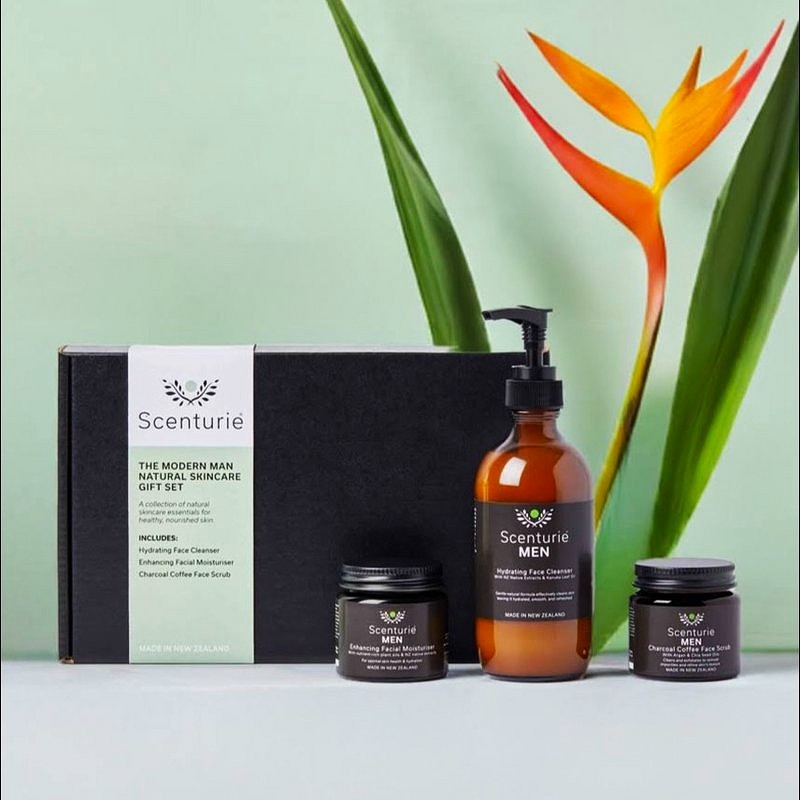 Scenturie Modern Man Natural Skincare Gift Set featuring the full-sized Cleanser, Scrub, and Moisturiser in front of a premium black gift box with a Bird of Paradise plant in the background.